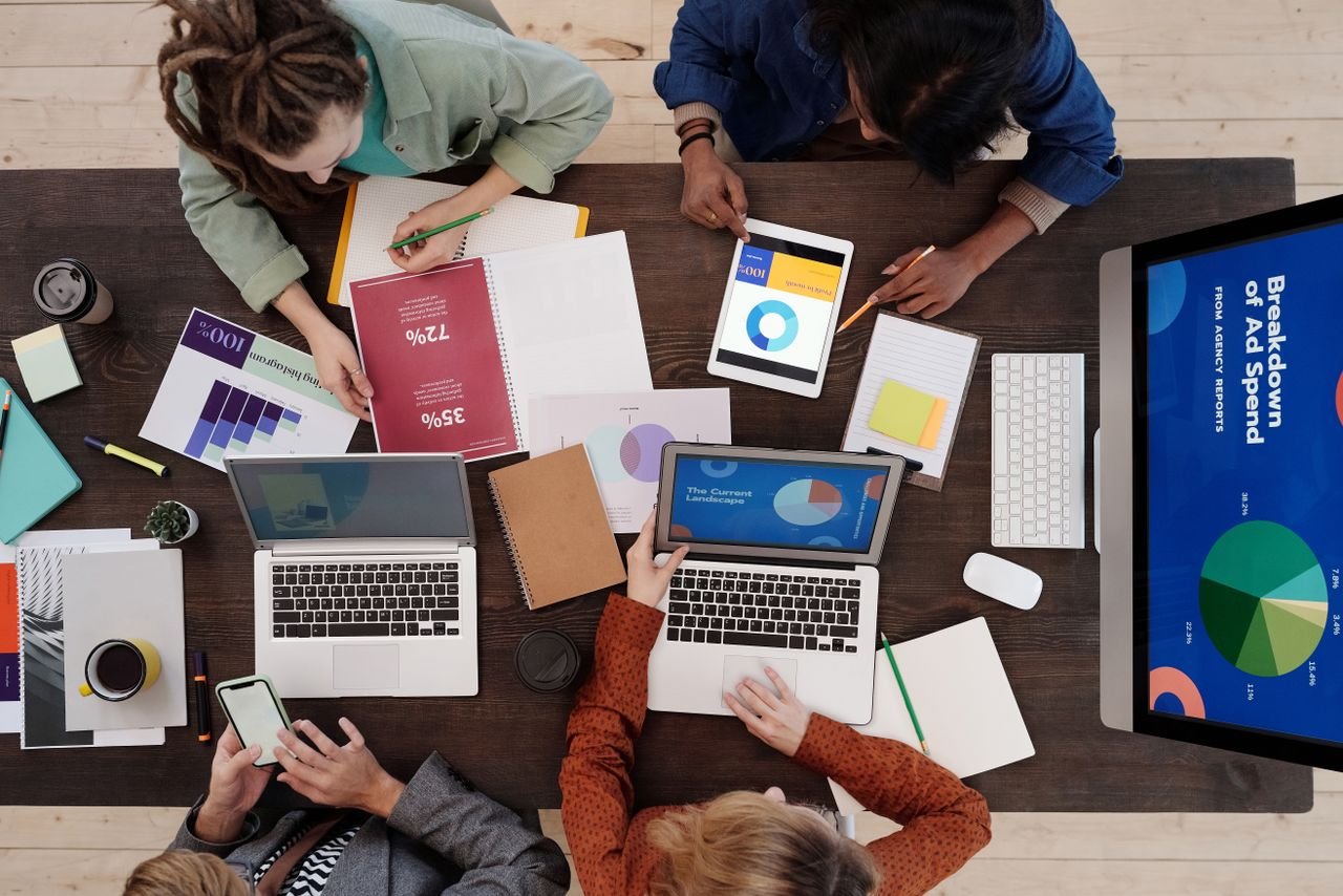 About A diverse team collaborating on digital marketing strategies at a desk, using laptops and tablets.